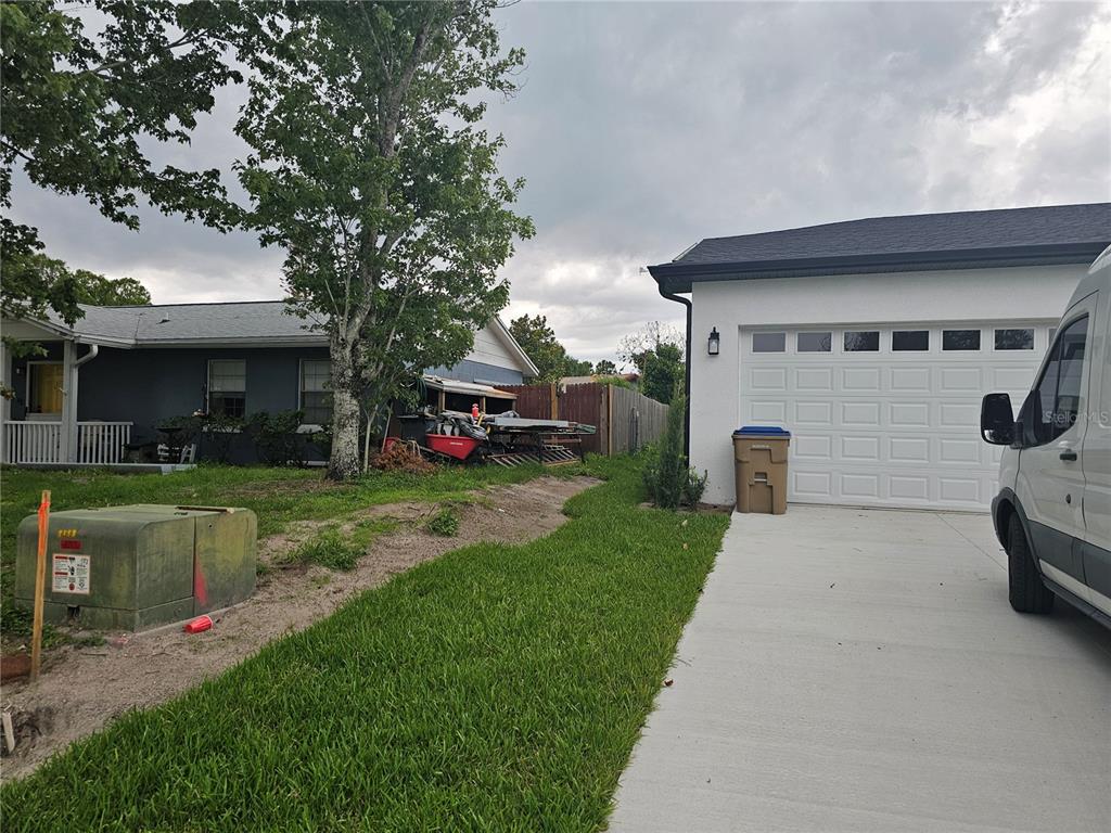 A view of a residential driveway, a white garage, and a neighboring house — 292 GARDENIA ROAD, KISSIMMEE, FL
