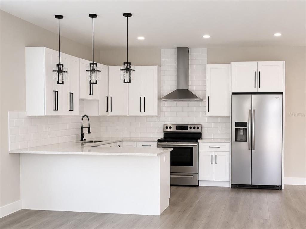 A modern kitchen features white cabinets, stainless steel appliances, a subway tile backsplash, and pendant lighting — 2045 27TH AVENUE N, ST PETERSBURG, FL