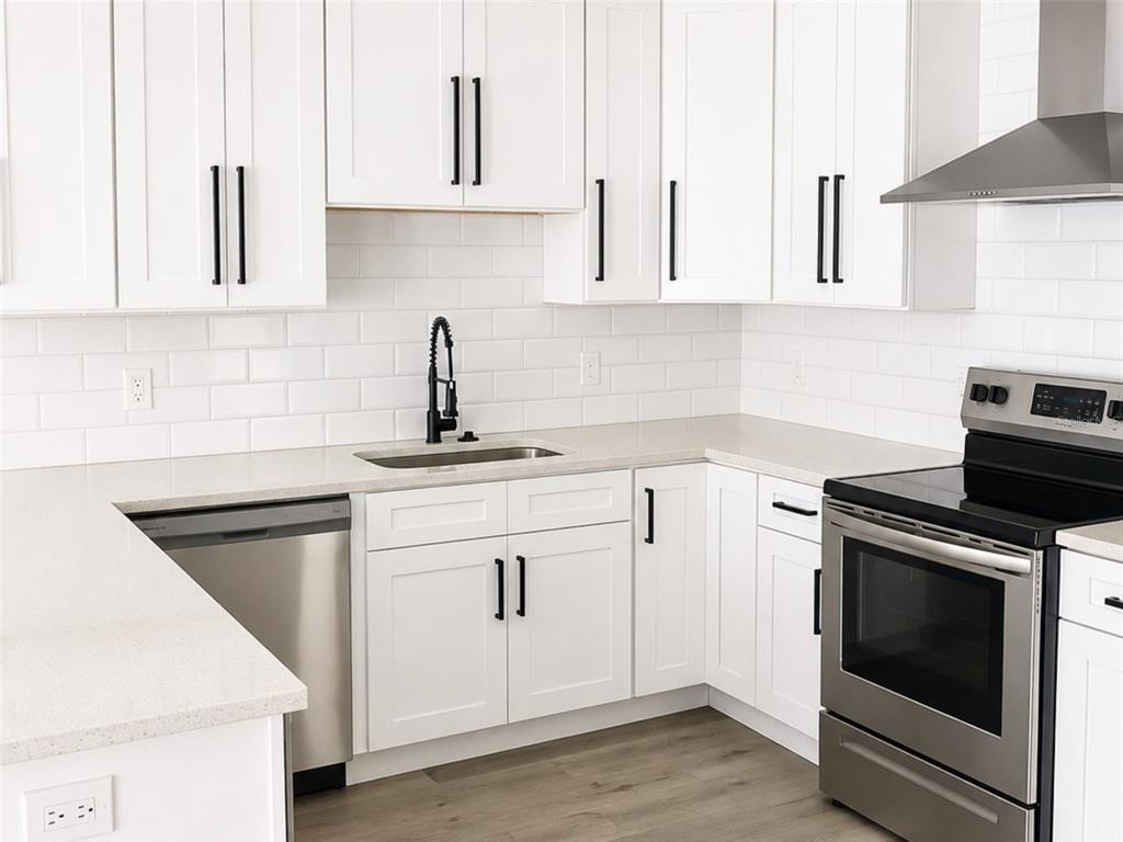 A modern kitchen features white cabinets, stainless steel appliances, a subway tile backsplash, and countertops — 2045 27TH AVENUE N, ST PETERSBURG, FL