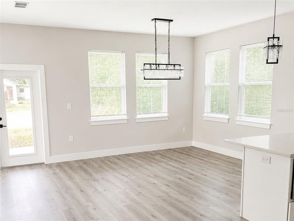 A dining area features light gray walls, wood-look flooring, four windows, and two hanging light fixtures — 2045 27TH AVENUE N, ST PETERSBURG, FL