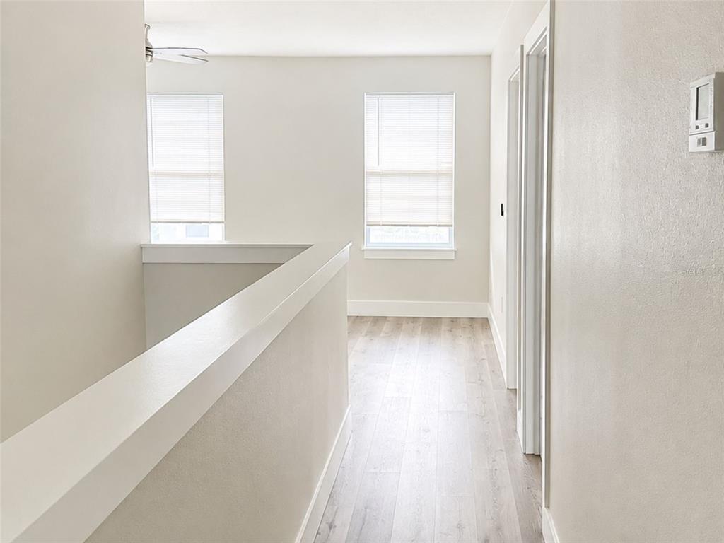 A bright hallway features light wood-look flooring, white walls, and two windows with blinds — 2045 27TH AVENUE N, ST PETERSBURG, FL
