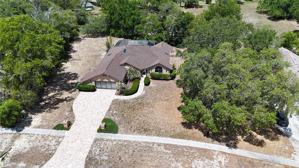 An aerial view shows a single-story brick house with a paved driveway and pool enclosure — 14692 LINDEN DRIVE, SPRING HILL, FL