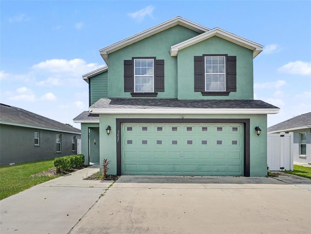 A two-story green house with a two-car garage and a concrete driveway — 3057 GRAND PRESERVE BOULEVARD, MULBERRY, FL