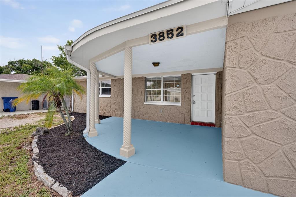 A house exterior features a curved covered porch with spiral columns and a stone-textured wall — 3852 SUNRAY DRIVE, HOLIDAY, FL