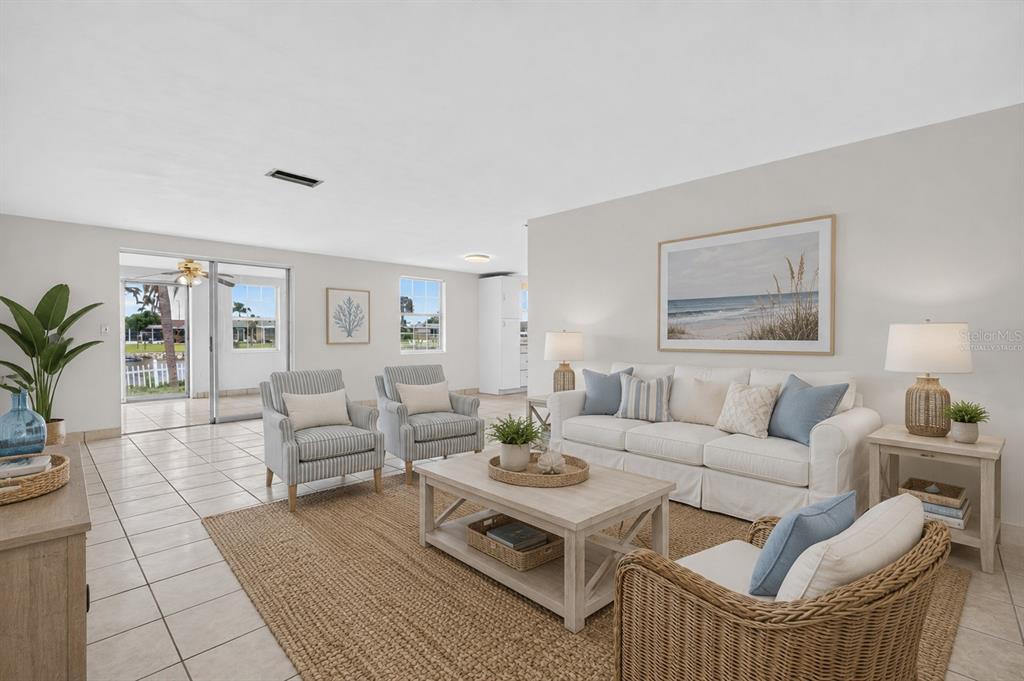 A living room with tile floors, a white sofa, armchairs, and a view of a patio — 3852 SUNRAY DRIVE, HOLIDAY, FL