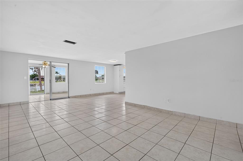 A spacious room with light-colored tile flooring, white walls, and a sliding glass door — 3852 SUNRAY DRIVE, HOLIDAY, FL