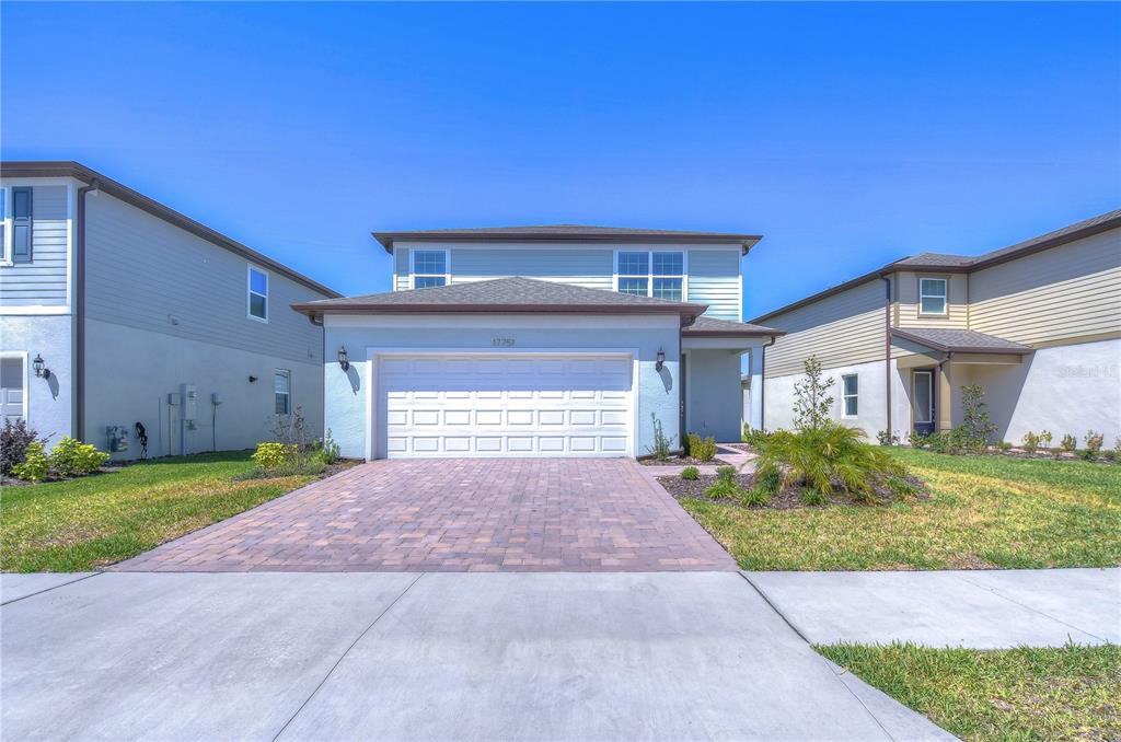 A two-story suburban house features a paved driveway, a two-car garage, and light-colored siding — 17751 EVERLONG DRIVE, LAND O LAKES, FL