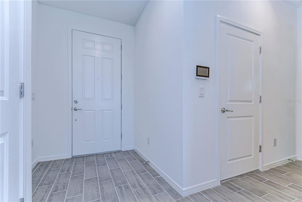 An entryway features white walls, gray wood-look tile flooring, and two white interior doors — 17751 EVERLONG DRIVE, LAND O LAKES, FL