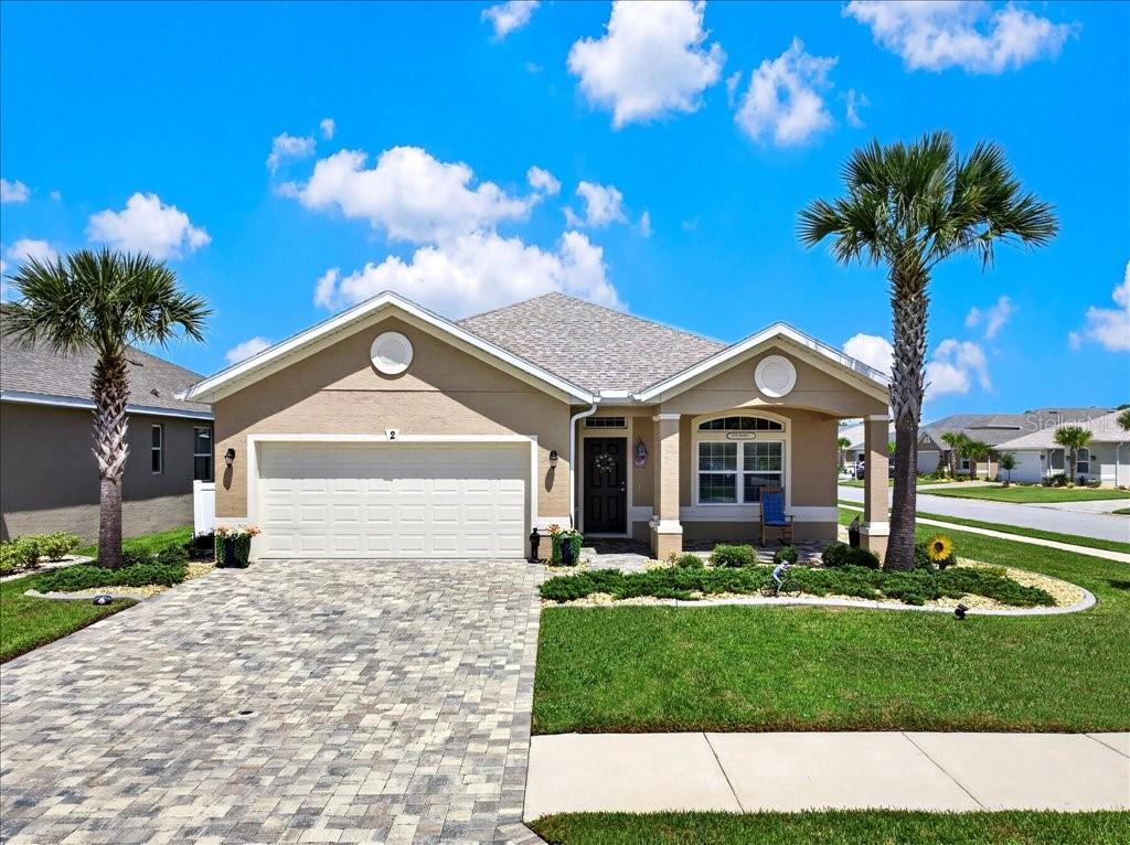 A single-story house with a beige stucco exterior, a paved driveway, and two palm trees — 2 TIDEWAY TRAIL, PALM COAST, FL