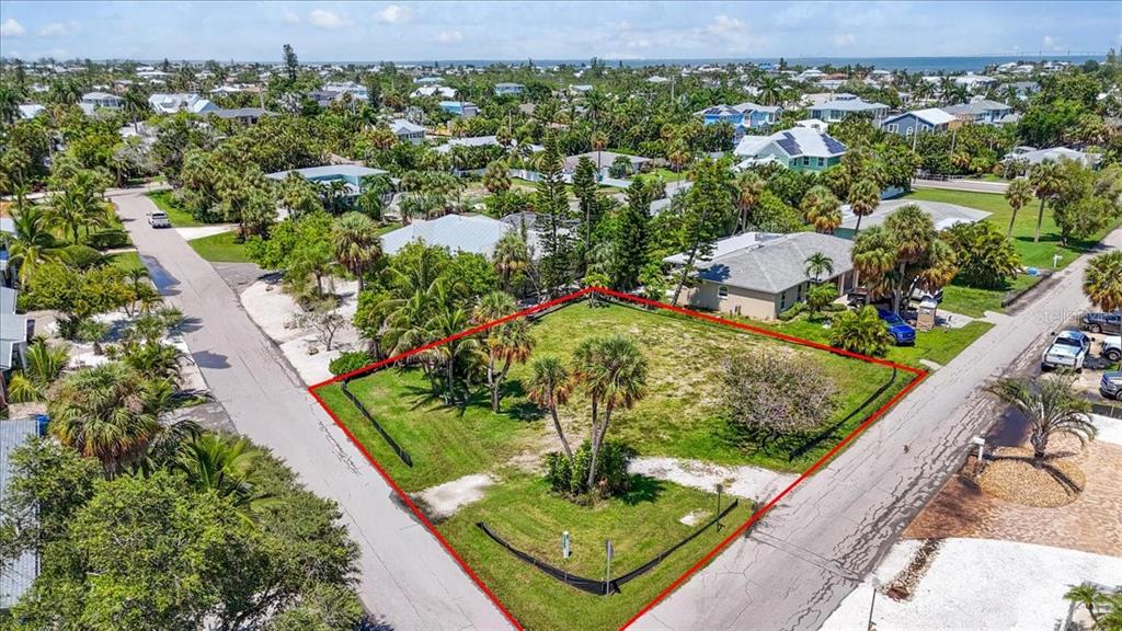 An aerial view shows a vacant corner lot outlined in red within a residential neighborhood — 302 73RD STREET, HOLMES BEACH, FL