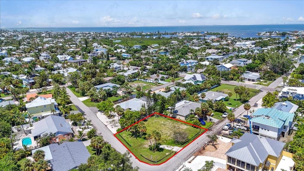 An aerial view shows a vacant, grass-covered residential lot outlined in red within a neighborhood — 302 73RD STREET, HOLMES BEACH, FL