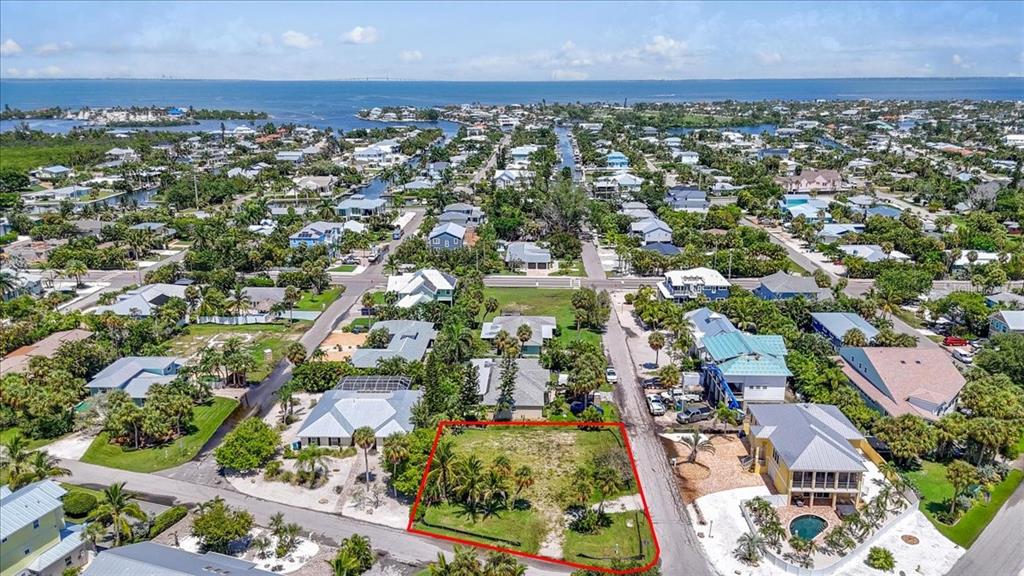 An aerial view shows a vacant, rectangular lot outlined in red within a coastal neighborhood — 302 73RD STREET, HOLMES BEACH, FL
