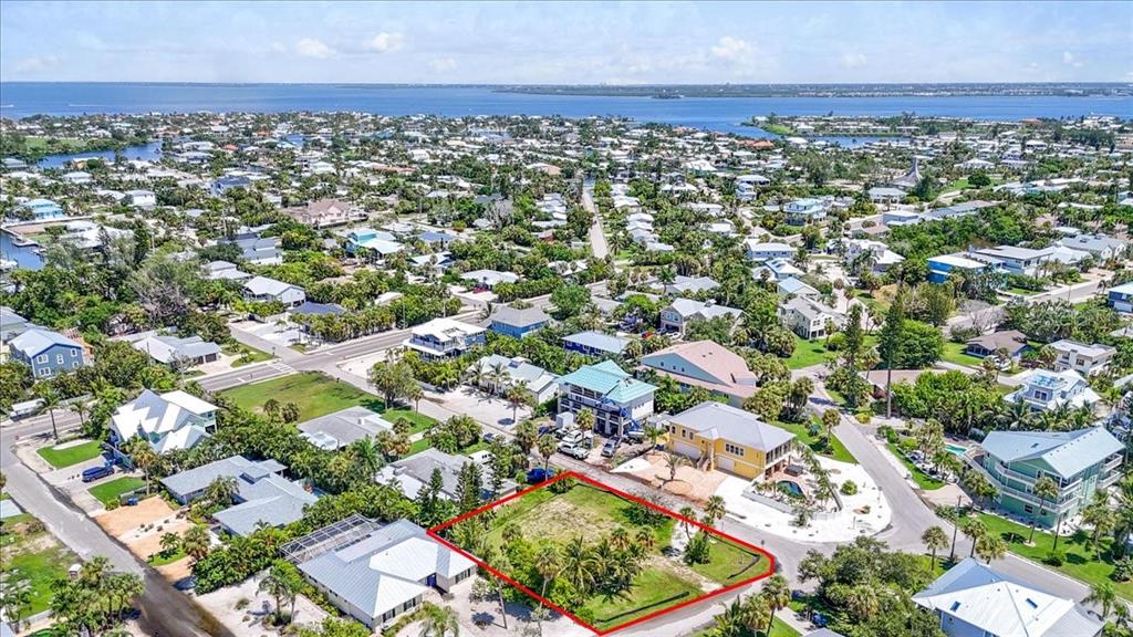 An aerial view shows a vacant, rectangular lot outlined in red within a coastal neighborhood — 302 73RD STREET, HOLMES BEACH, FL