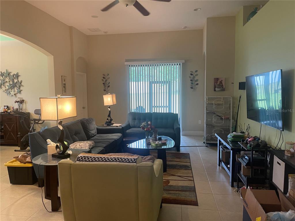 A living room features tile flooring, a large television, and two dark blue sofas — 824 VINO VERDE CIRCLE, BRANDON, FL