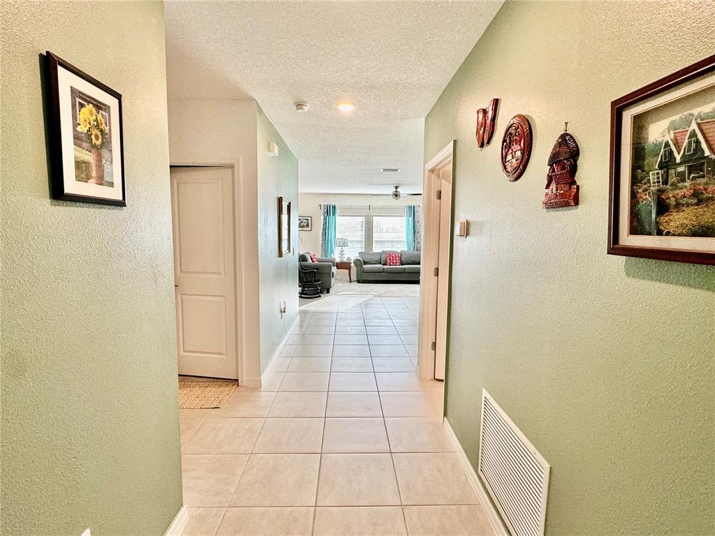 A tiled hallway leads into a living room with light green walls and framed artwork — 993 CALICO POINTE CIRCLE, GROVELAND, FL