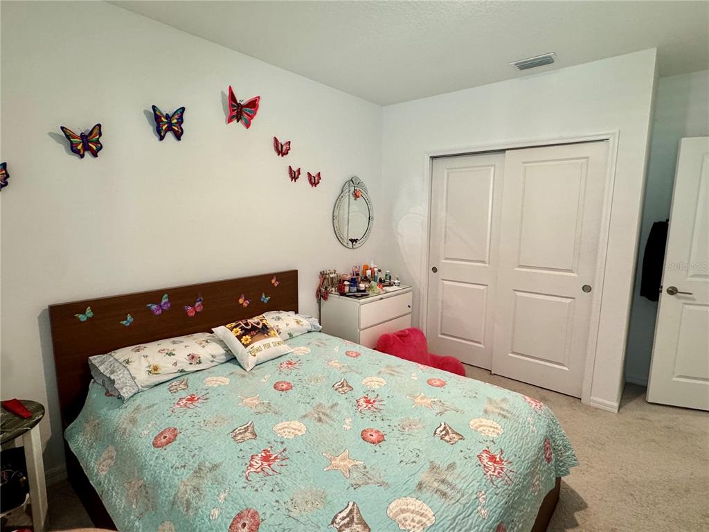 A bedroom features a bed with a sea-themed quilt, butterfly wall decor, and white doors — 993 CALICO POINTE CIRCLE, GROVELAND, FL