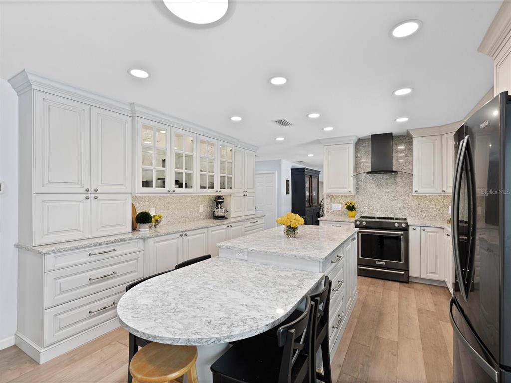 A kitchen features white cabinetry, granite countertops, a central island, and black appliances — 2285 WATROUS DRIVE, DUNEDIN, FL