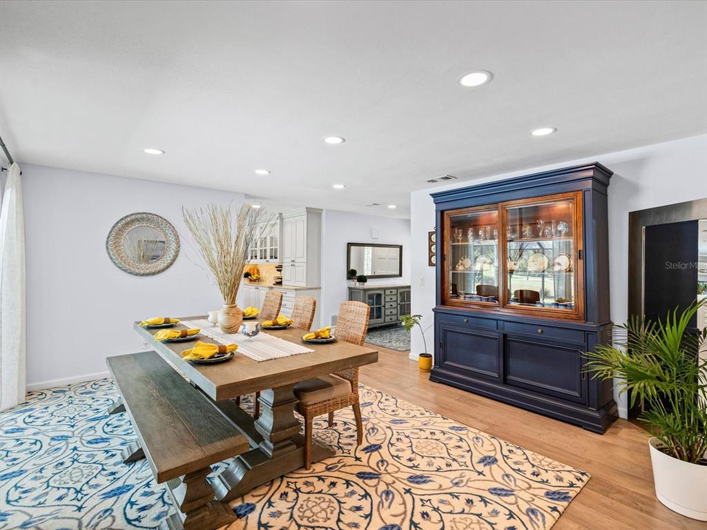 A dining room features a wooden table, a bench, wicker chairs, and a large blue hutch — 2285 WATROUS DRIVE, DUNEDIN, FL