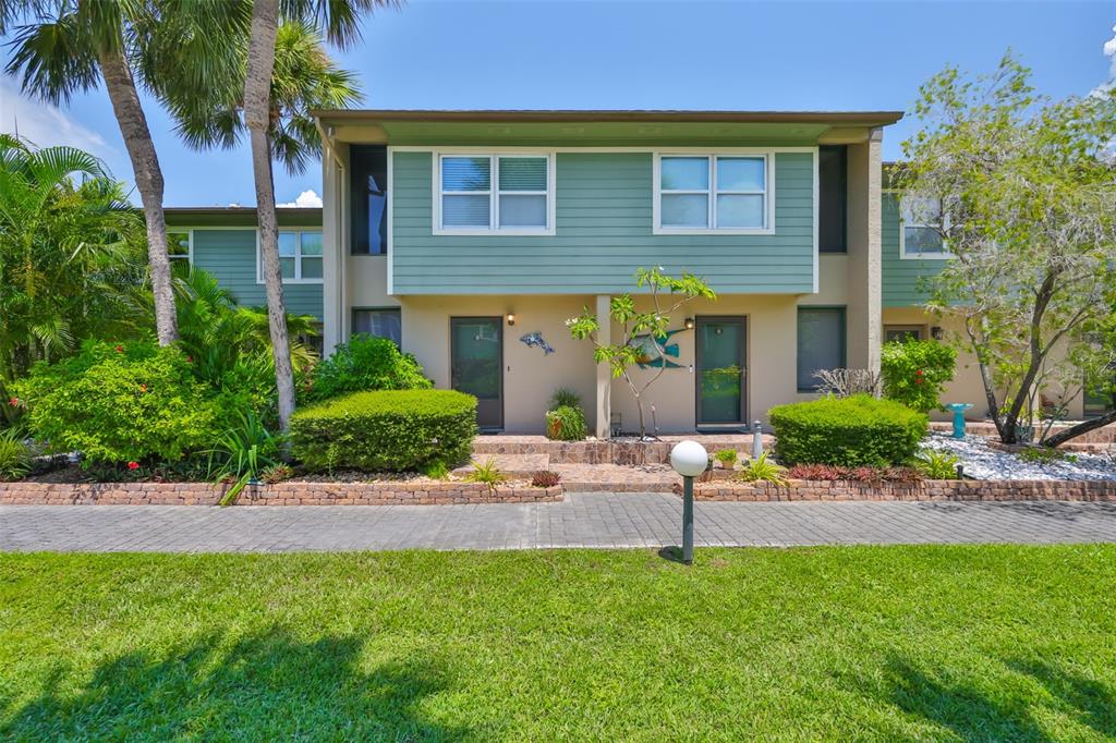 A two-story townhouse with green siding, a stone walkway, and landscaped front gardens — 1028 APOLLO BEACH BOULEVARD UNIT 8, APOLLO BEACH, FL