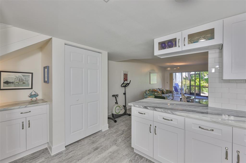 A kitchen with white cabinets and marble countertops overlooks a living area and screened patio — 1028 APOLLO BEACH BOULEVARD UNIT 8, APOLLO BEACH, FL