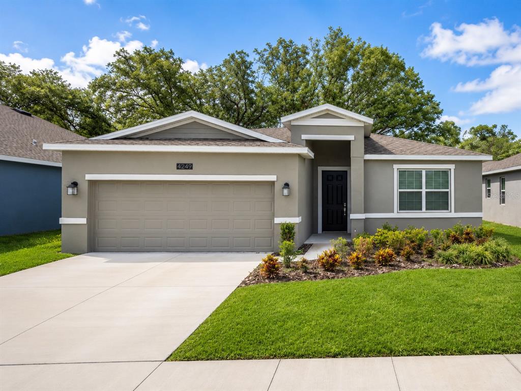 A single-story house with a two-car garage, gray stucco exterior, and a landscaped front yard — 4249 BABBLING BROOK WAY, KISSIMMEE, FL