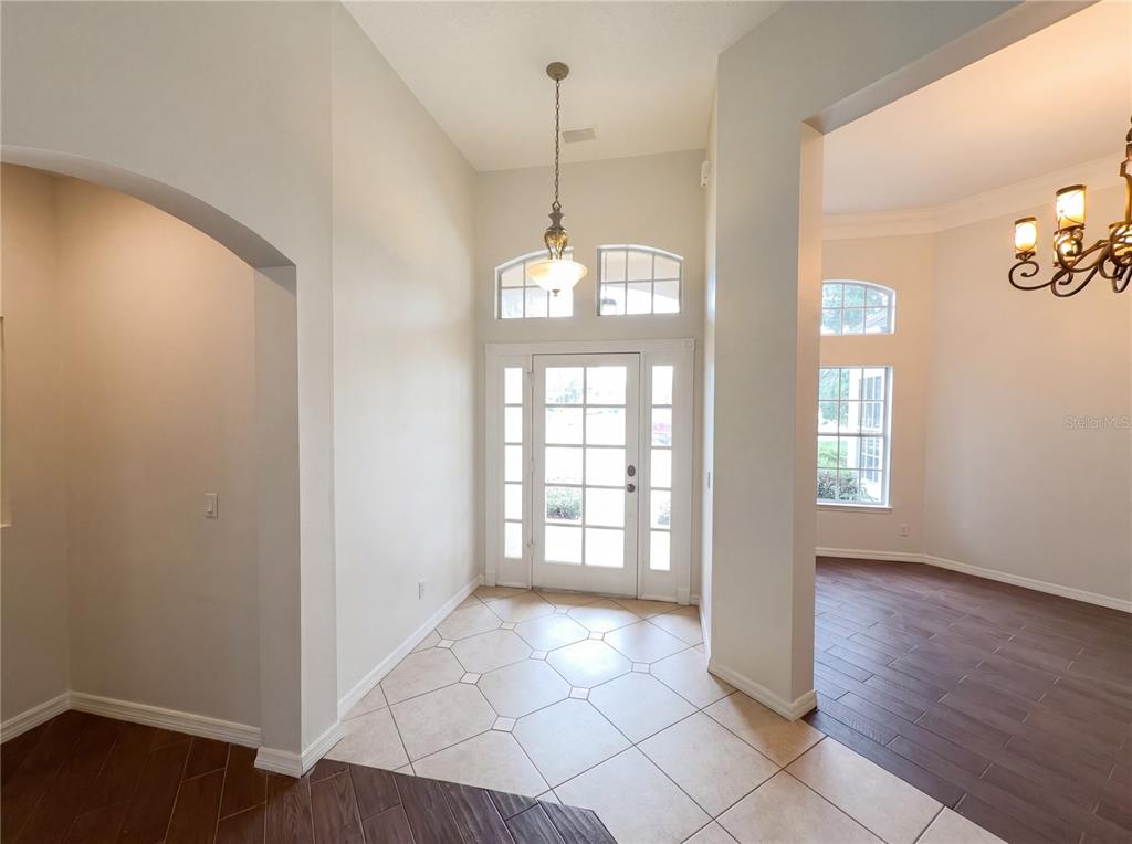 A foyer features a glass-paneled front door, tile flooring, and an arched entryway to another room — 680 MACGLENROSS DRIVE, OVIEDO, FL