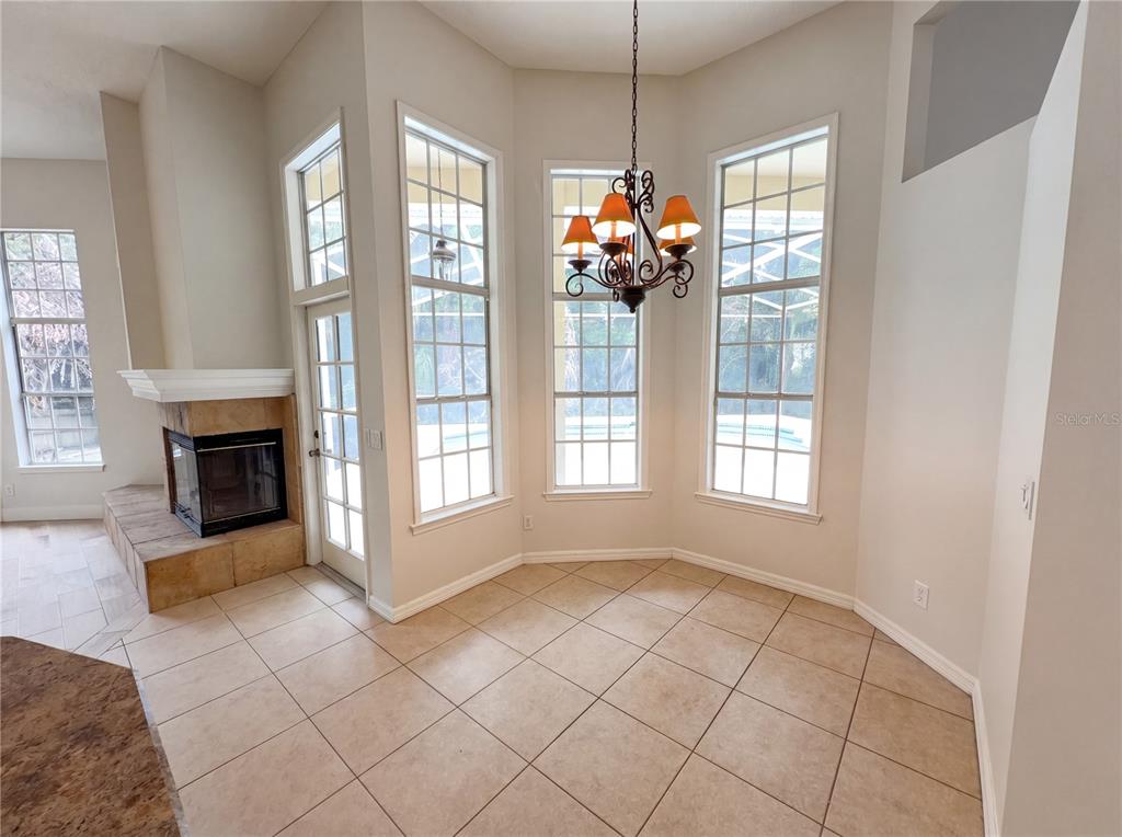A breakfast nook with tile flooring, a fireplace, and a bay window overlooking a pool — 680 MACGLENROSS DRIVE, OVIEDO, FL
