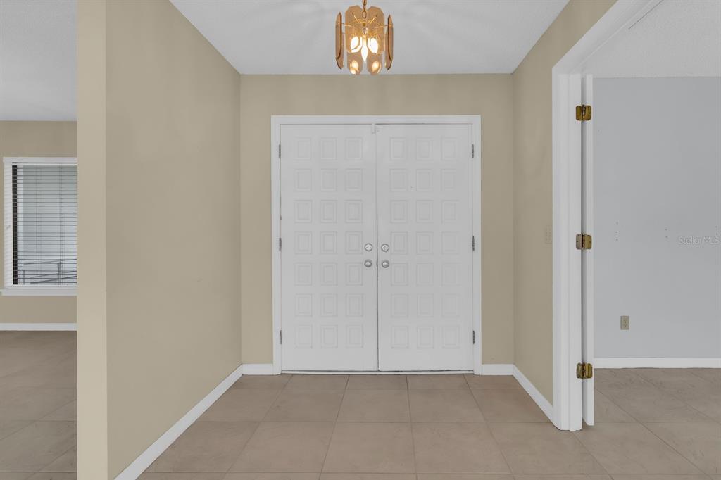 An entryway features a double white door, beige walls, and light-colored tile flooring — 381 HAVERLAKE CIRCLE, APOPKA, FL