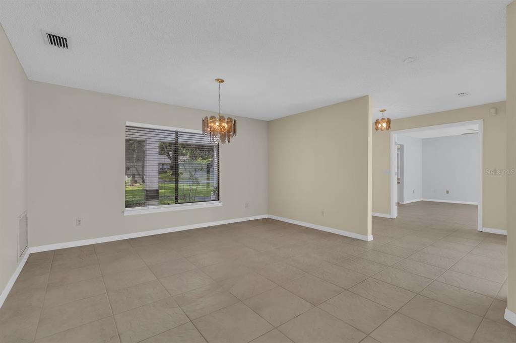 A dining room with beige walls, tile flooring, a chandelier, and a large window — 381 HAVERLAKE CIRCLE, APOPKA, FL
