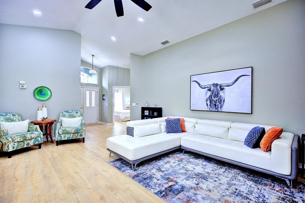 A living room features a white sectional sofa, two patterned armchairs, and a longhorn wall art — 1011 TEQUESTA TRAIL, LAKE WALES, FL