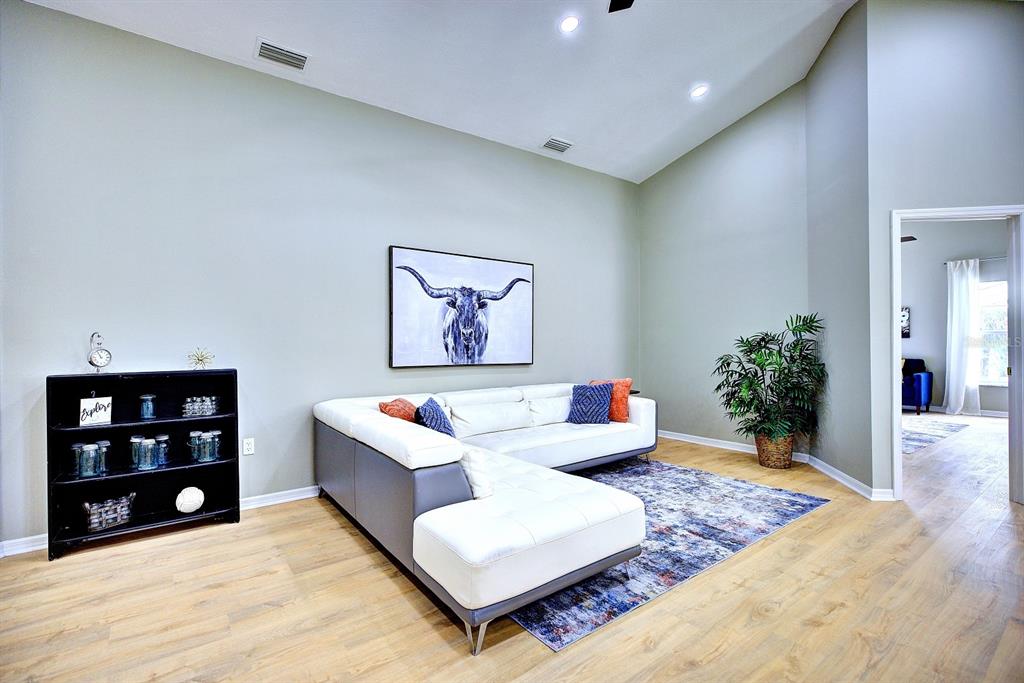 A living room features a white sectional sofa, a black bookshelf, and a longhorn wall art — 1011 TEQUESTA TRAIL, LAKE WALES, FL