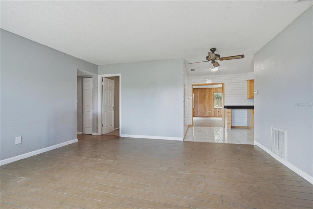 A living room with light gray walls, wood-look tile flooring, and a ceiling fan — 1412 ORMOND AVENUE, APOPKA, FL