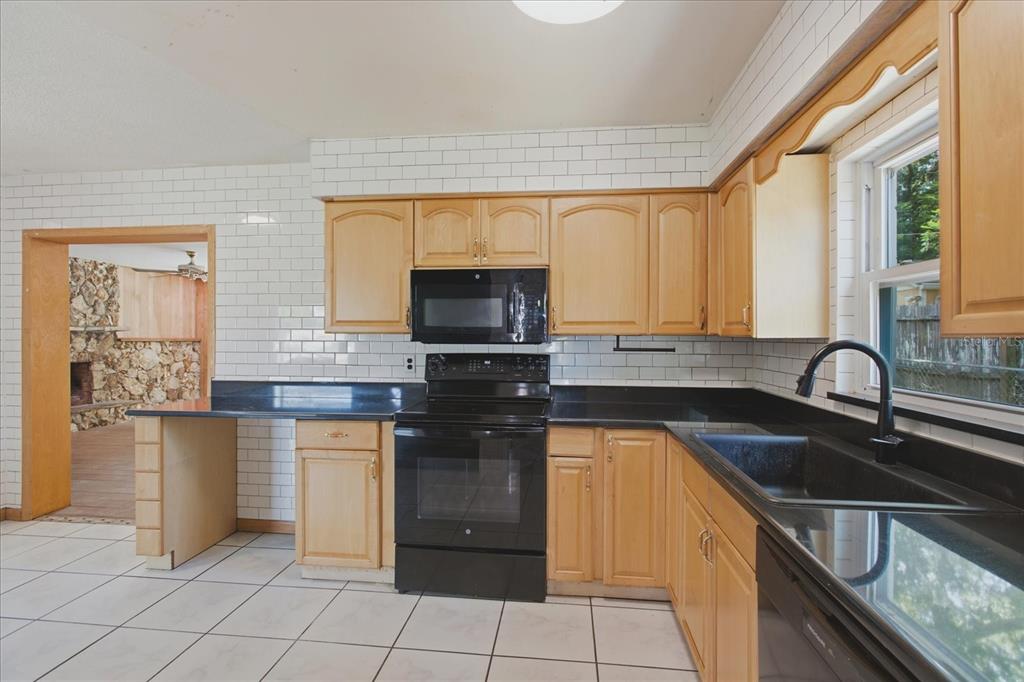 A kitchen with light wood cabinets, black countertops, white subway tile walls, and tile flooring — 1412 ORMOND AVENUE, APOPKA, FL