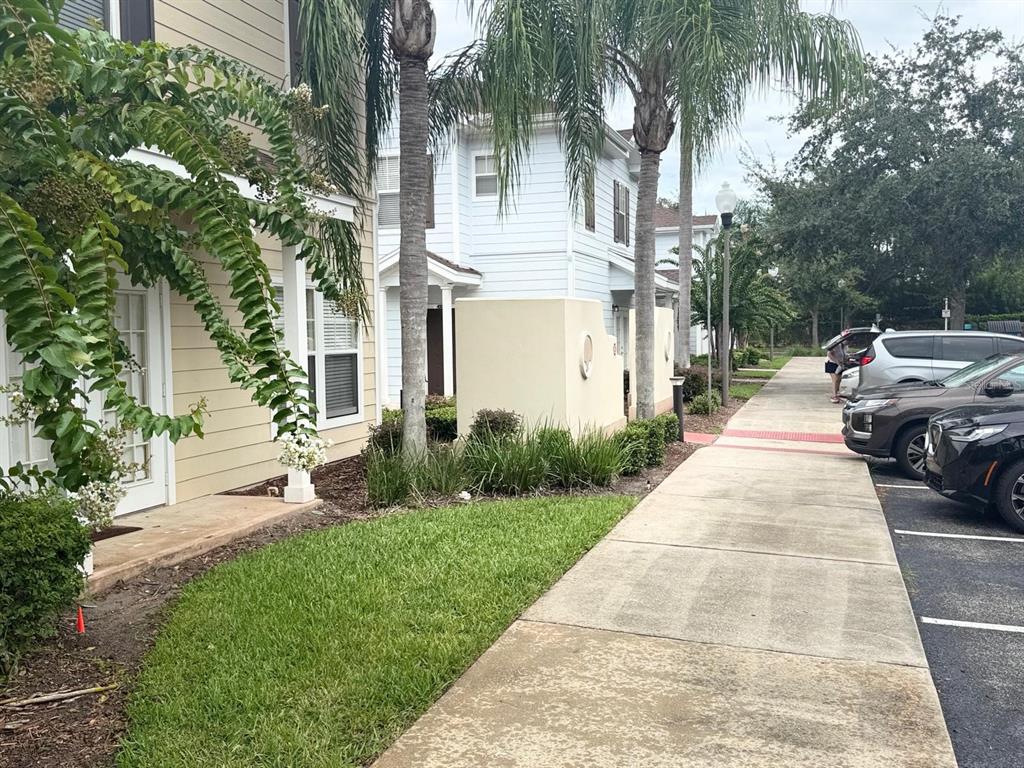 A sidewalk runs alongside a tan building and a white building with palm trees — 2952 LUCAYAN HARBOUR CIRCLE UNIT 103, KISSIMMEE, FL