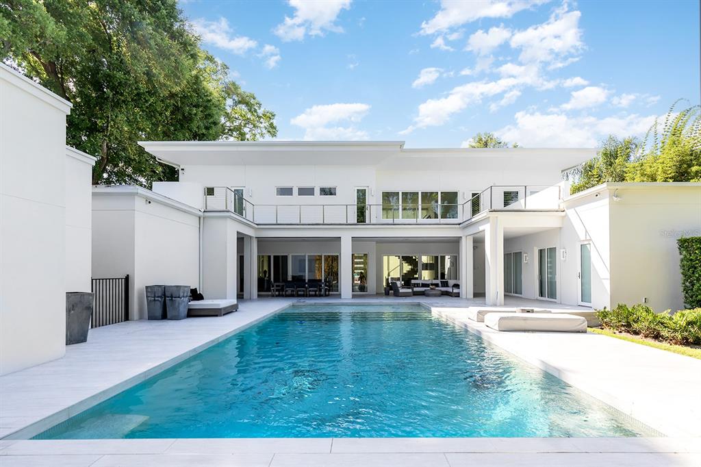 A modern white two-story house features a rectangular swimming pool and a spacious patio area — 231 CHELTON CIRCLE, WINTER PARK, FL