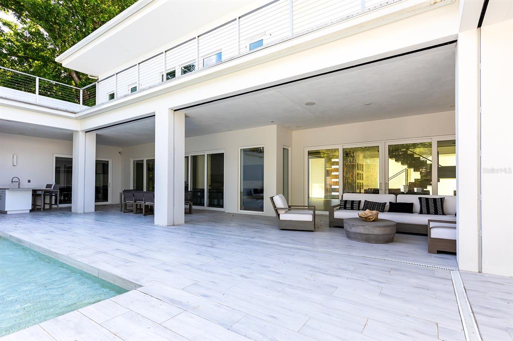 A modern patio with light tile flooring features a pool, outdoor seating, and sliding doors — 231 CHELTON CIRCLE, WINTER PARK, FL