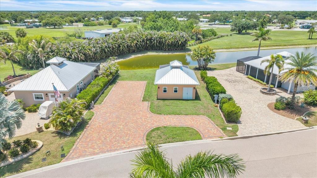 An aerial view shows two houses and a detached garage with paver driveways near a pond — 8168 SW SAND CRANE CIRCLE, ARCADIA, FL