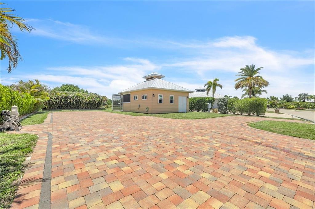A tan detached garage with a metal roof sits at the end of a paver driveway — 8168 SW SAND CRANE CIRCLE, ARCADIA, FL