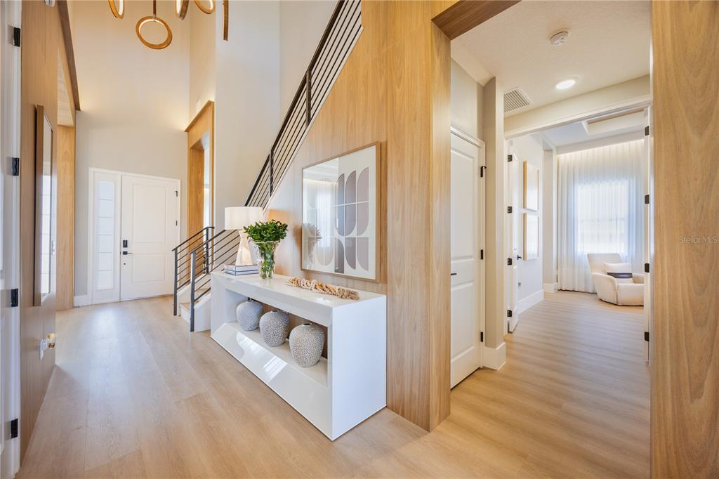 A bright living room features a curved white sofa, a tiered coffee table, and wood accents — 16077 BARKLY RIDGE COURT, WINTER GARDEN, FL