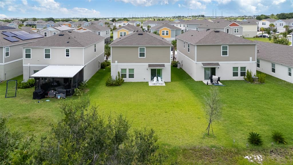 An aerial view shows the backyards and rear exteriors of three suburban two-story houses — 5528 SUMMER SUNSET DRIVE, APOLLO BEACH, FL