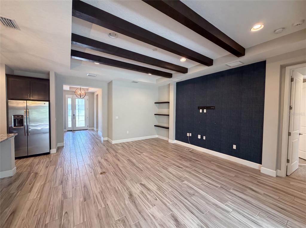 A living room features wood-look tile flooring, dark ceiling beams, and a navy blue accent wall — 1011 VICTORIA HILLS DRIVE S, DELAND, FL