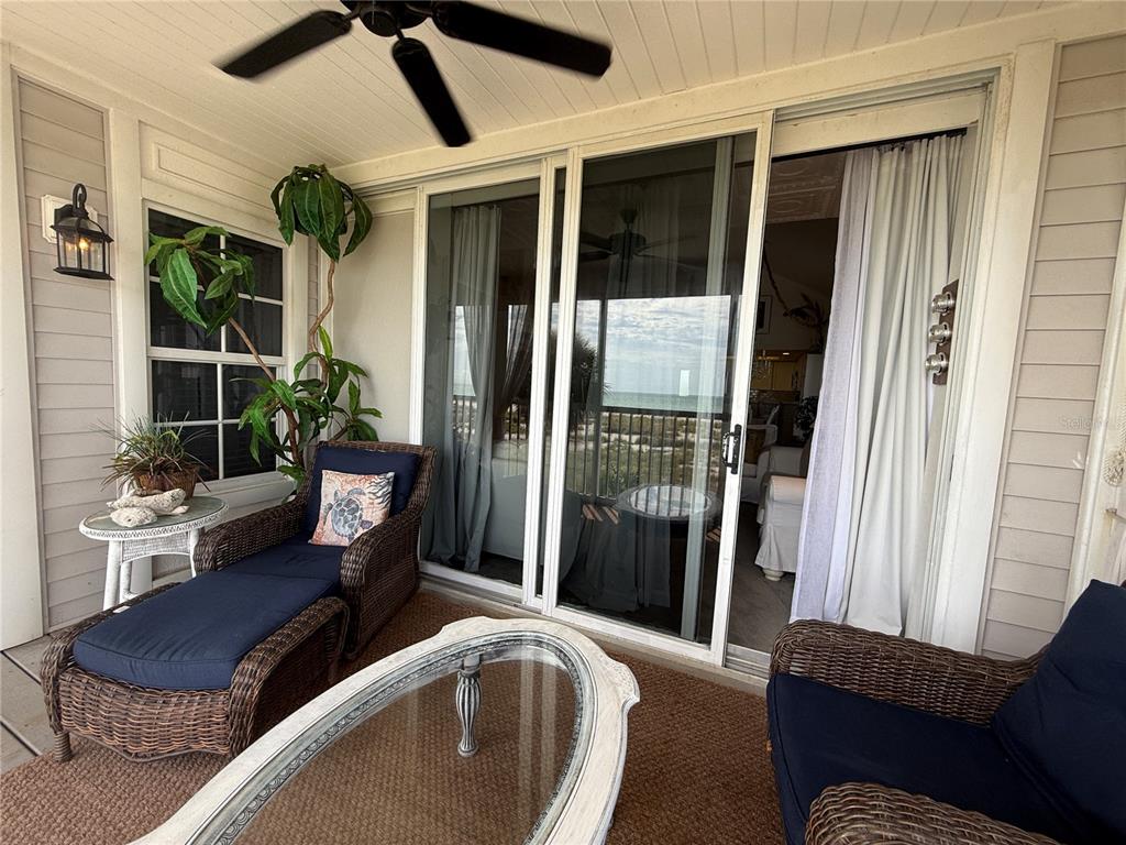 A covered patio features wicker furniture, a glass-top coffee table, and sliding doors overlooking water — 7500 PLACIDA ROAD UNIT 2124, PLACIDA, FL