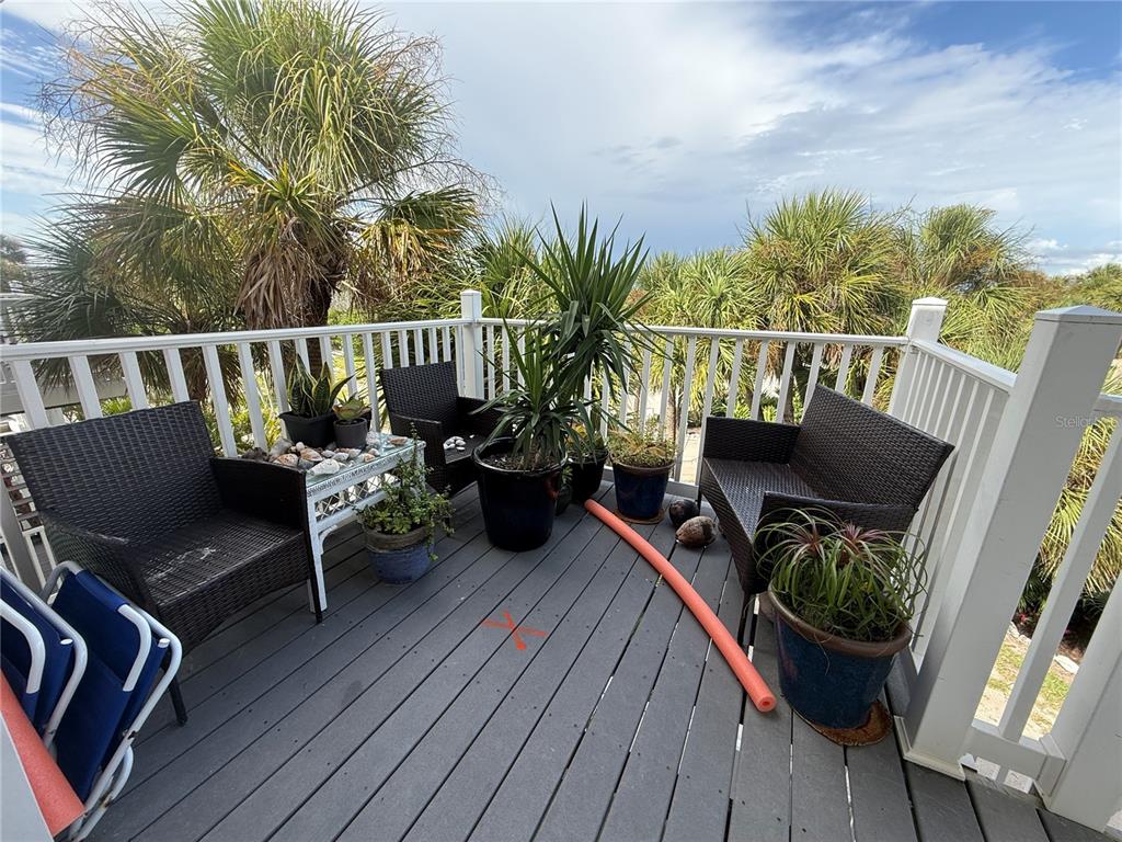 A wooden deck features wicker patio furniture, potted plants, and a pool noodle — 7500 PLACIDA ROAD UNIT 2124, PLACIDA, FL