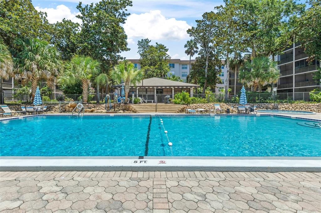 A rectangular swimming pool with a depth marker sits in front of a clubhouse building — 640 N NOVA ROAD UNIT 209, ORMOND BEACH, FL