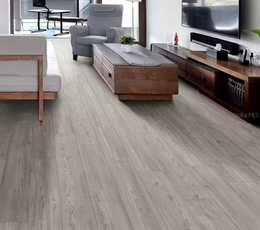 A living room features gray wood-look flooring, a wooden coffee table, and a media console — 2820 SAN MARCO WAY E, WINTER HAVEN, FL