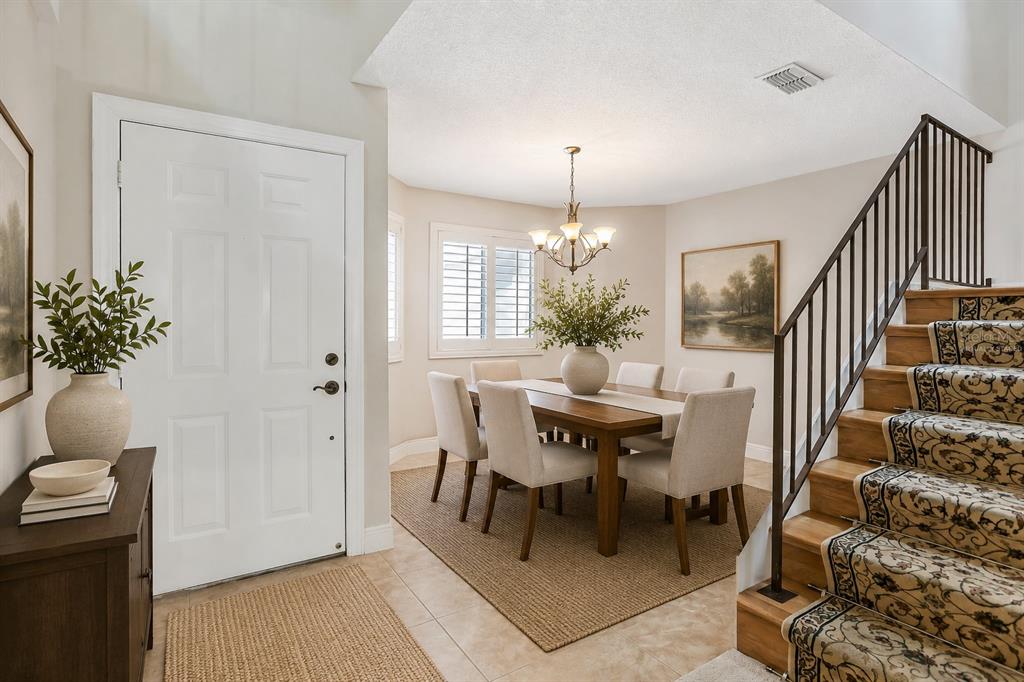 A dining area with a wooden table and chairs sits beside an entryway and staircase — 605 CHESTNUT OAK CIRCLE UNIT 107, ALTAMONTE SPRINGS, FL