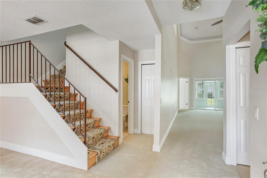 An interior view shows a carpeted staircase with a metal railing next to a hallway — 605 CHESTNUT OAK CIRCLE UNIT 107, ALTAMONTE SPRINGS, FL