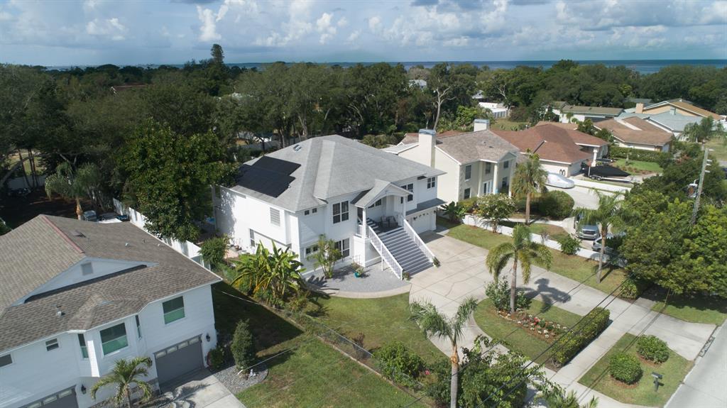An aerial view shows a white two-story house with solar panels and a front staircase — 1605 GULF ROAD, TARPON SPRINGS, FL