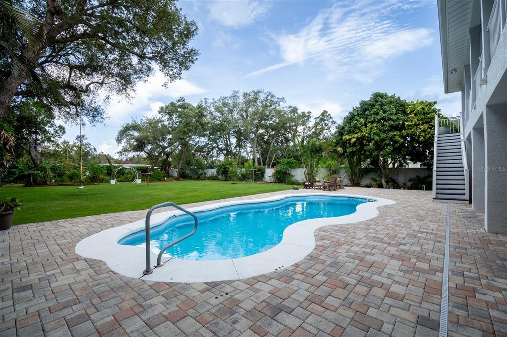A backyard features a kidney-shaped swimming pool, a brick paver deck, and a grassy lawn — 1605 GULF ROAD, TARPON SPRINGS, FL