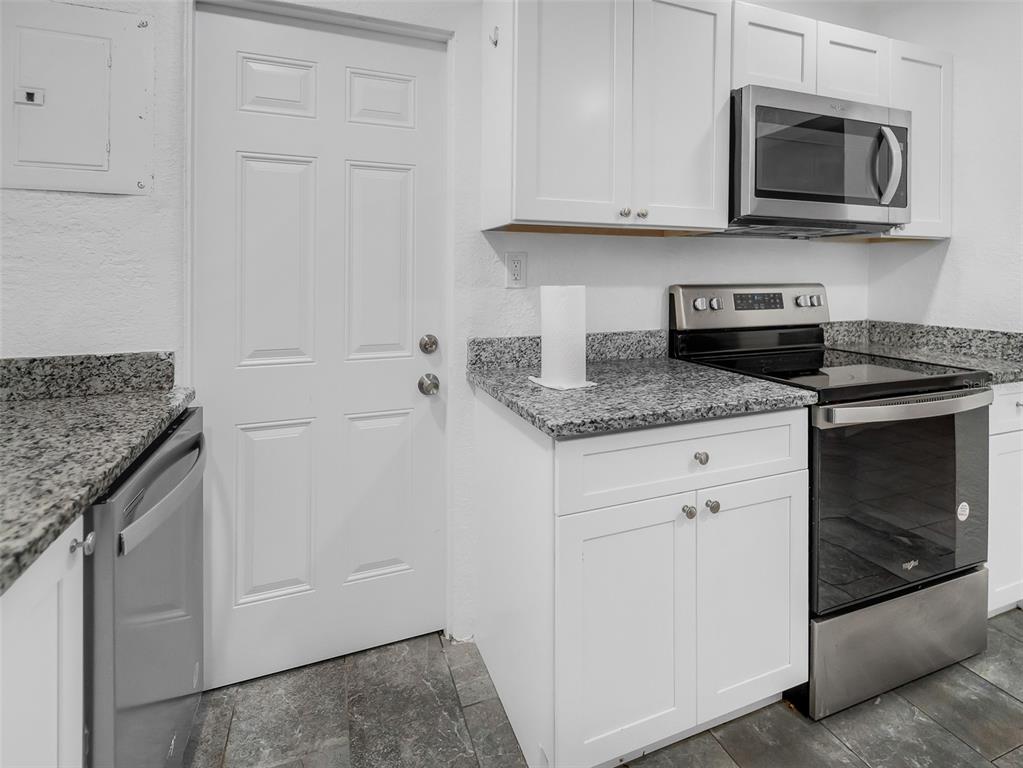 A kitchen features white cabinets, granite countertops, stainless steel appliances, and a white door — 2600 EUSTON ROAD, WINTER PARK, FL
